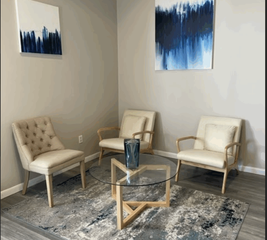 Modern salon waiting area with stylish chairs and contemporary artwork.